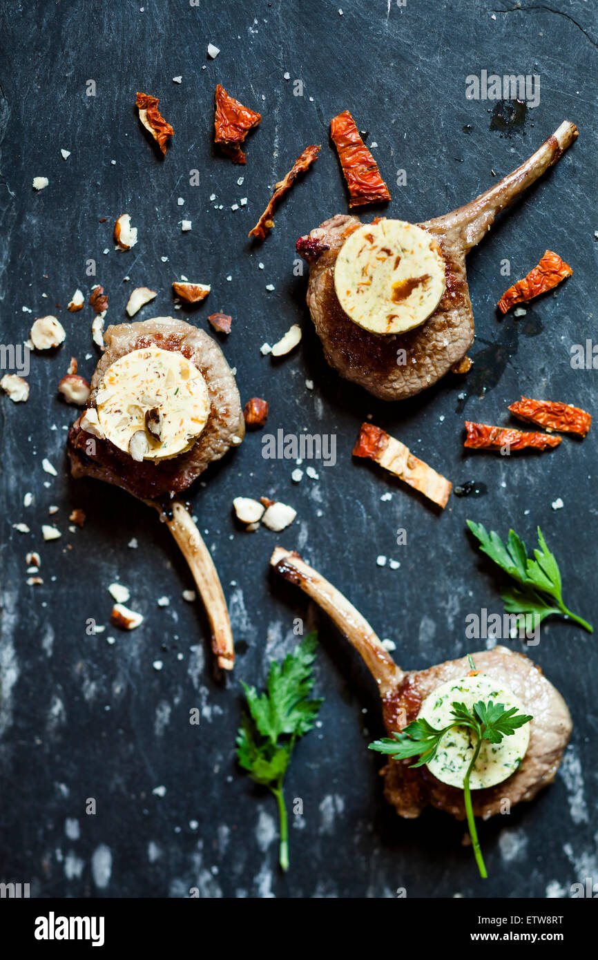 Three differently flavoured compound butters on lamb chops and parsley