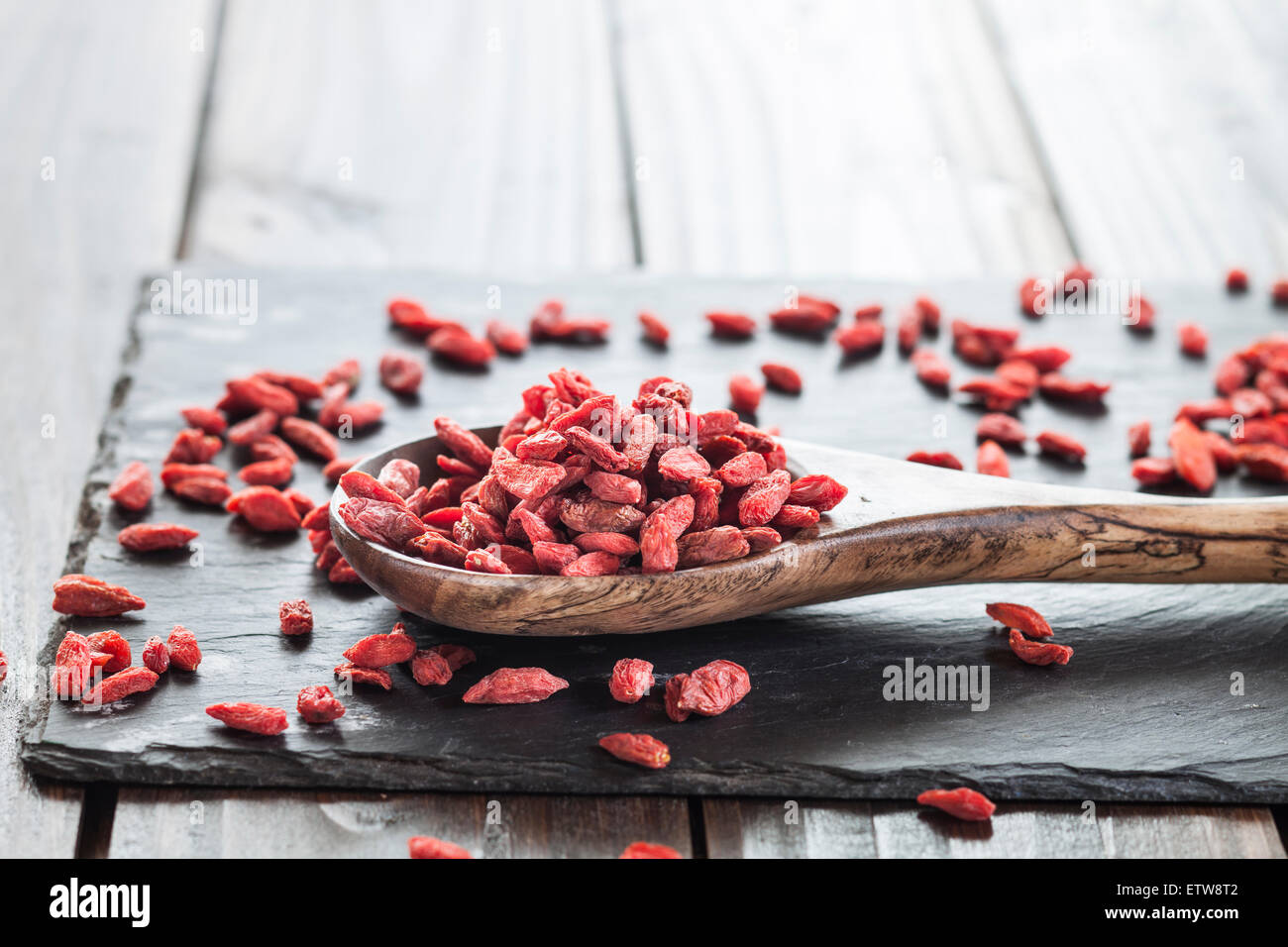 Wooden spoon with goji berries on a slate, superfood Stock Photo
