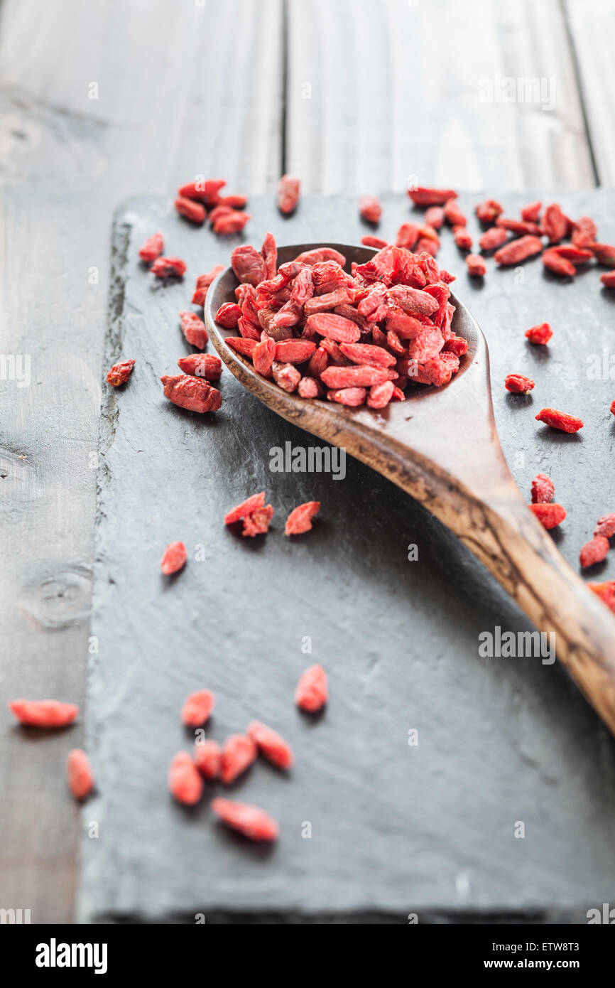 Wooden spoon with goji berries on a slate, superfood Stock Photo