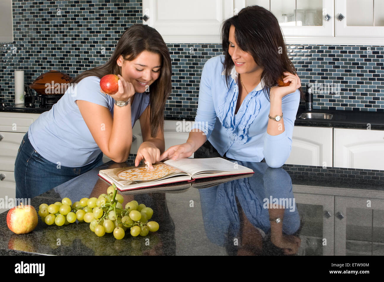 Two friends discussing recipes over a cookbook Stock Photo