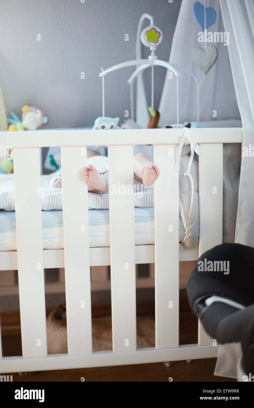 Baby lying in crib with feet sticking out Stock Photo Alamy