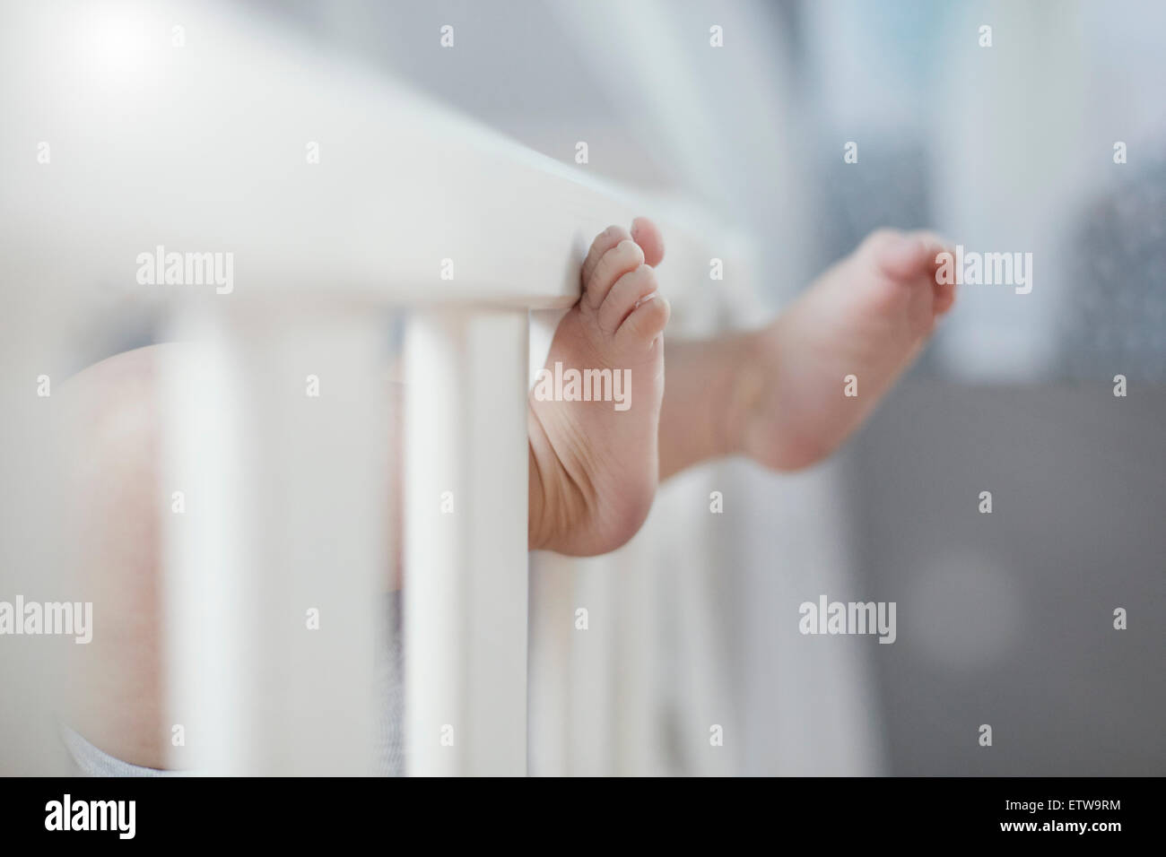 Baby lying in crib with feet sticking out Stock Photo Alamy