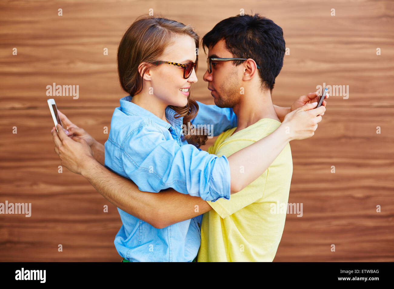 Young couple in embrace using smartphones Stock Photo