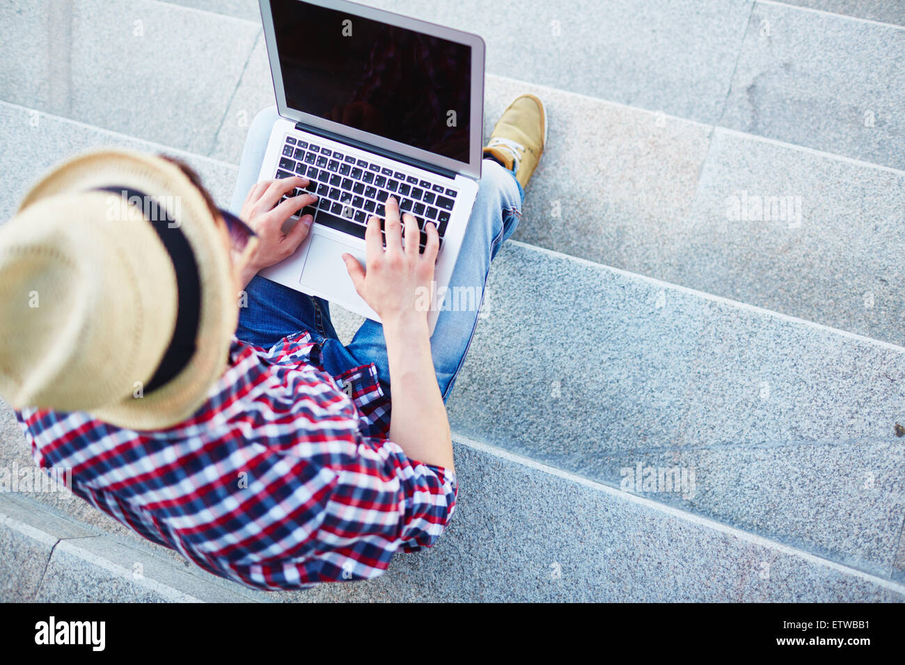 Modern guy typing on laptop while sitting on stairs Stock Photo - Alamy