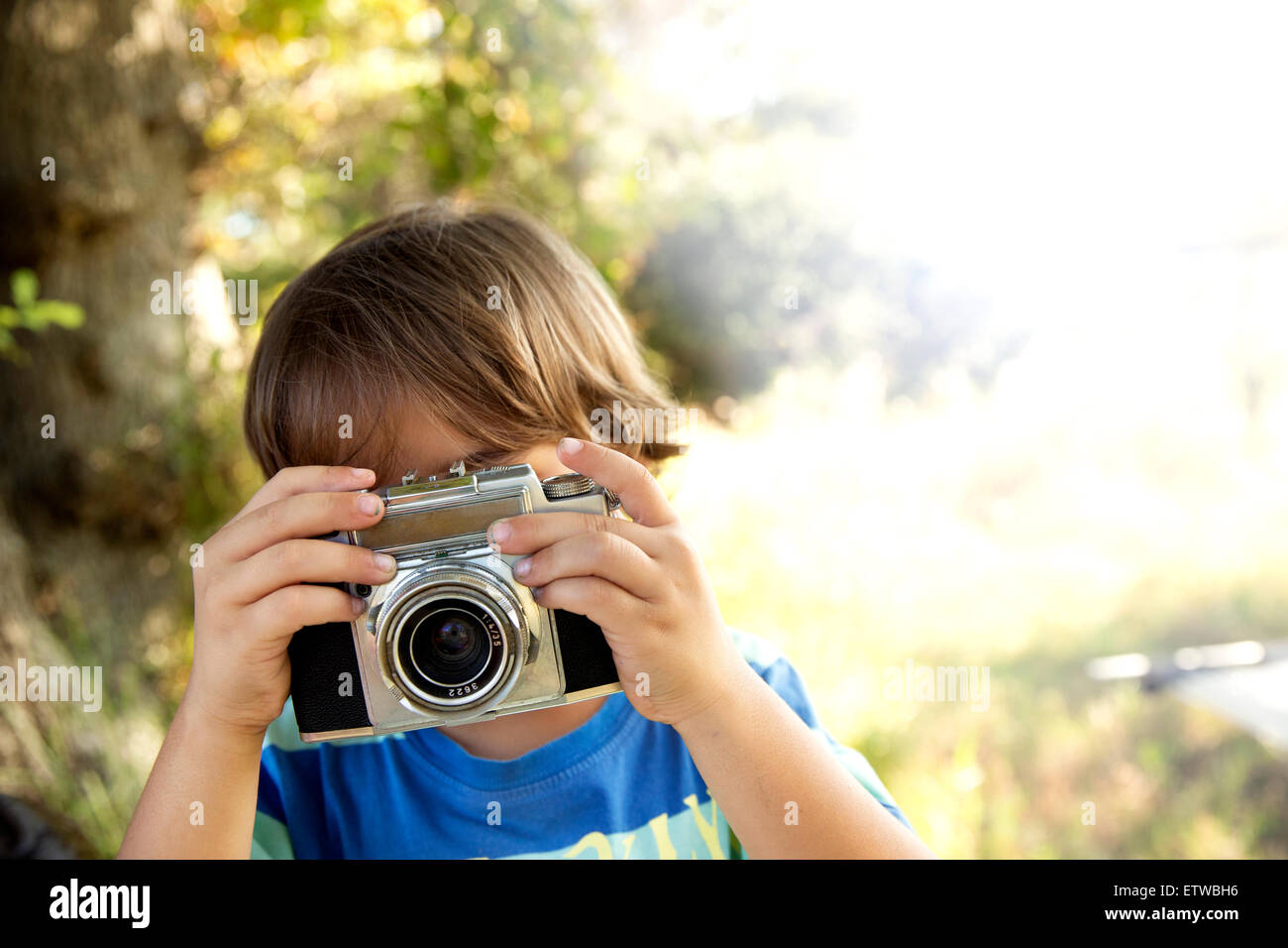 Boy with analog camera taking a picture outdoors Stock Photo - Alamy