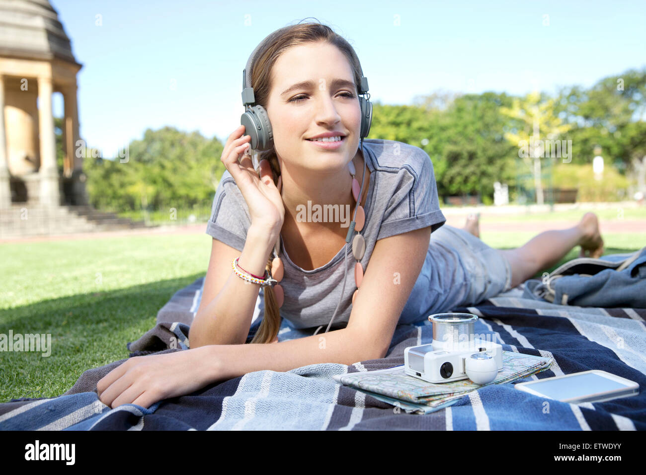 Young woman lying on blanket in park listening to music Stock Photo - Alamy