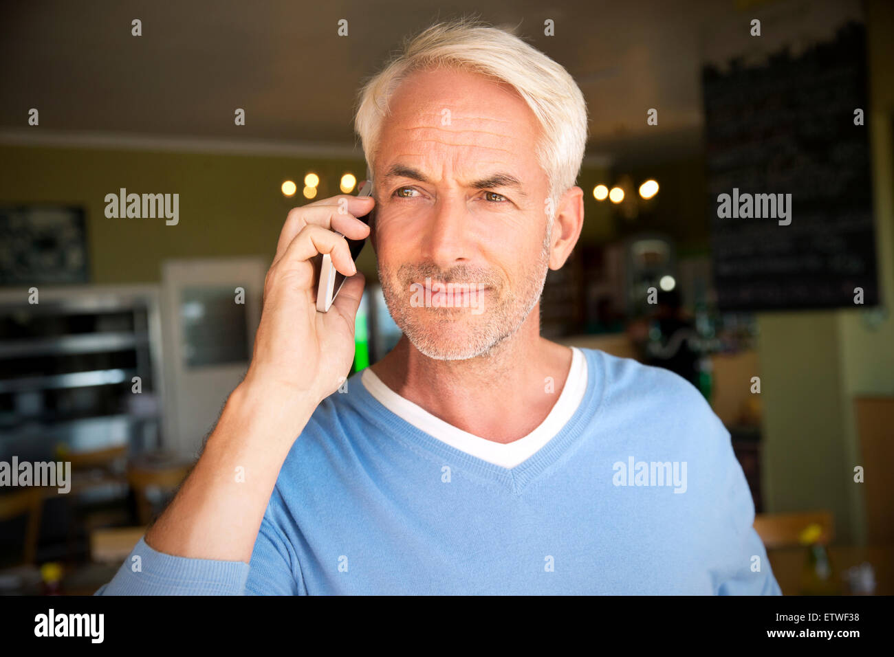 Portrait of white haired man telephoning with smartphone in a cafe Stock Photo