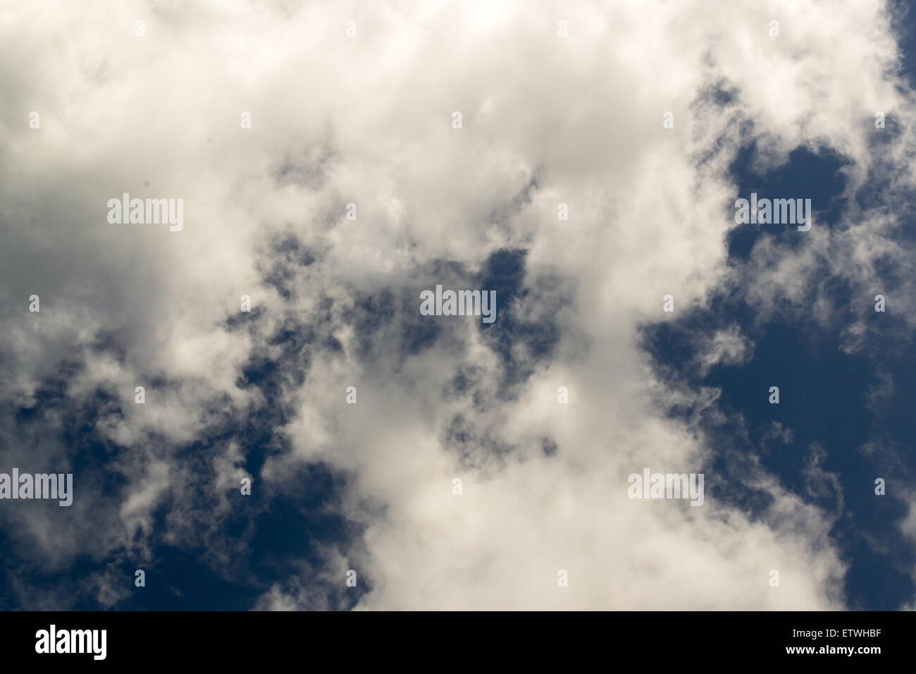 White feathery clouds against a rich blue sky with no land or people Stock Photo