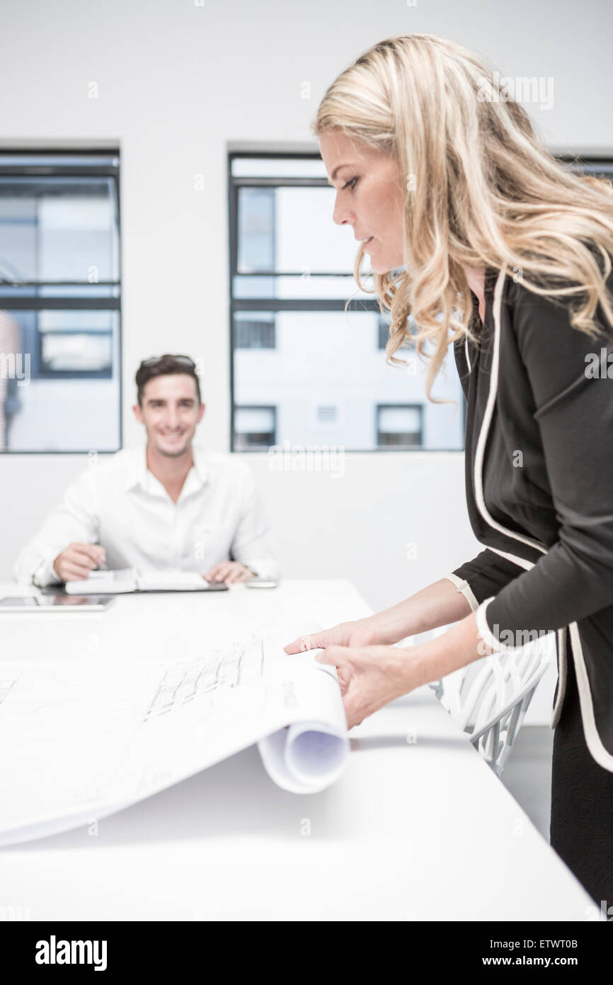 Businesswoman in office rolling up constuction plan Stock Photo