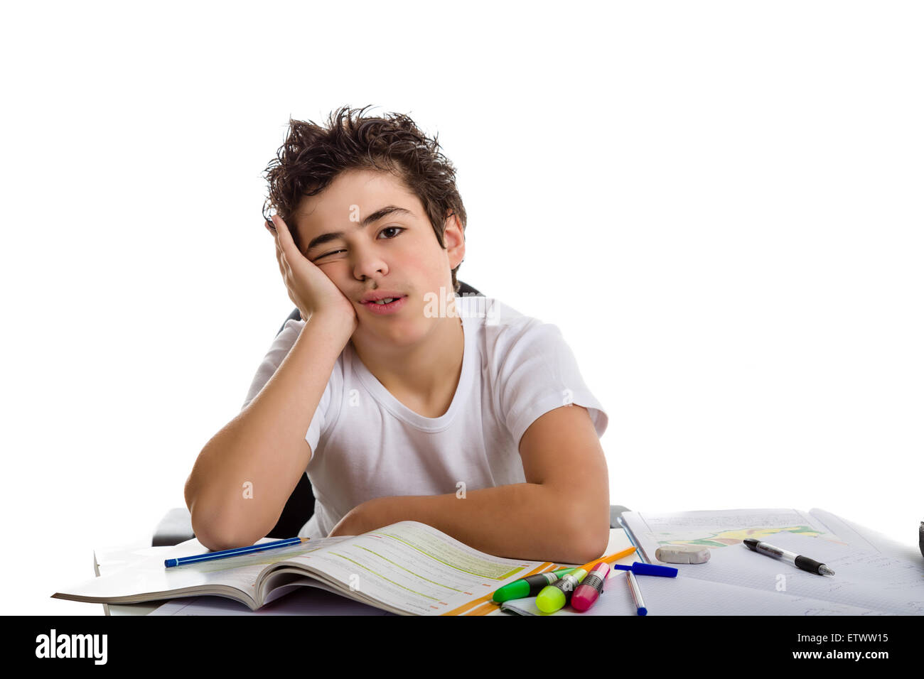 Tired  boy holds his face doing his  homework: he is sadly sitting in front of books,copybooks and pencils Stock Photo