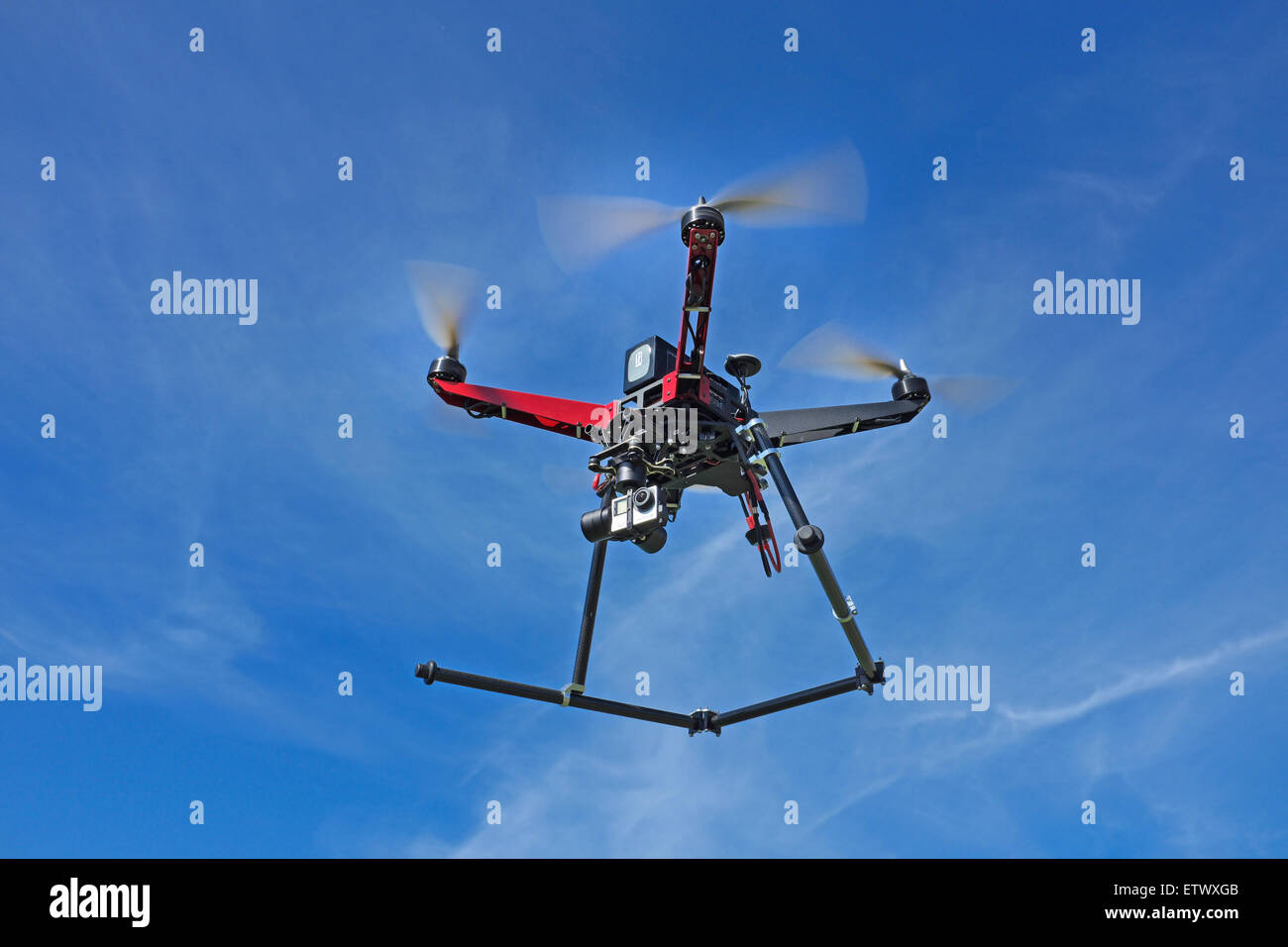 A quadcopter drone, equipped with a gopro camera, in flight. Stock Photo