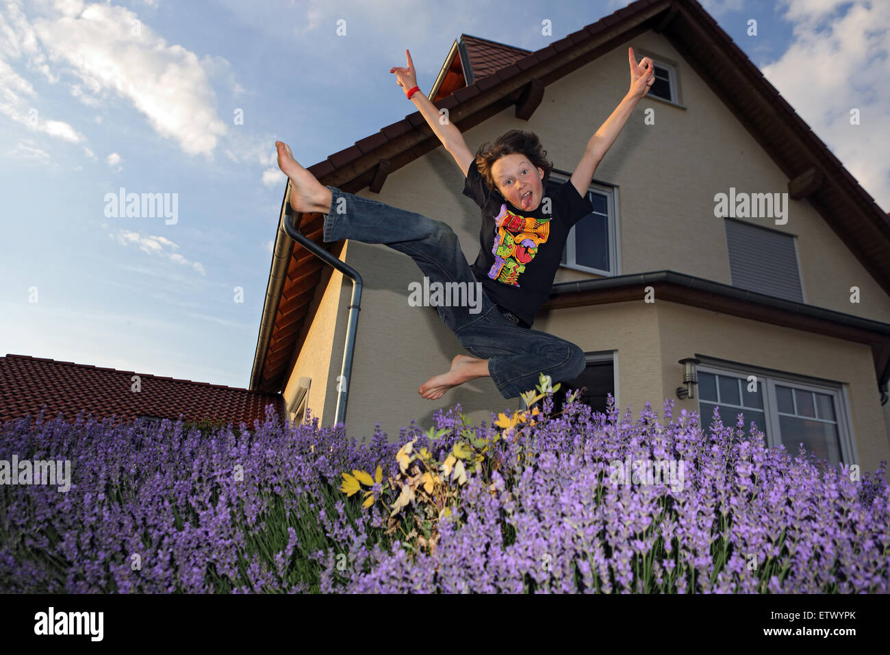 Werl, Germany, Young makes a leap into the air in front of a single-family house Stock Photo