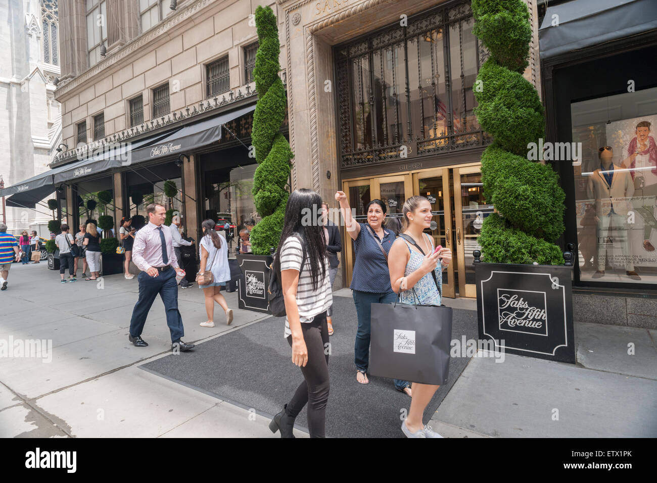 Shoppers outside of the Saks Fifth Avenue flagship store in New York on Thursday, June 11, 2015. Hudson's Bay, the Canadian owner of Saks and Lord & Taylor, reported a first-quarter loss of CA $54 million citing administrative expenses and costs related to sales. The Saks division rose 0.6 % while its outlet brand OFF 5th  rose 10.3 %. (© Richard B. Levine) Stock Photo