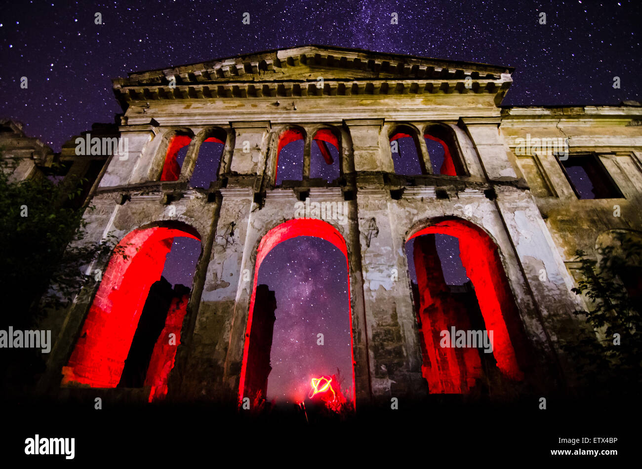 The night sky and the Milky Way, and highlighted the unusual red silhouette of the ruined walls of the old building Stock Photo