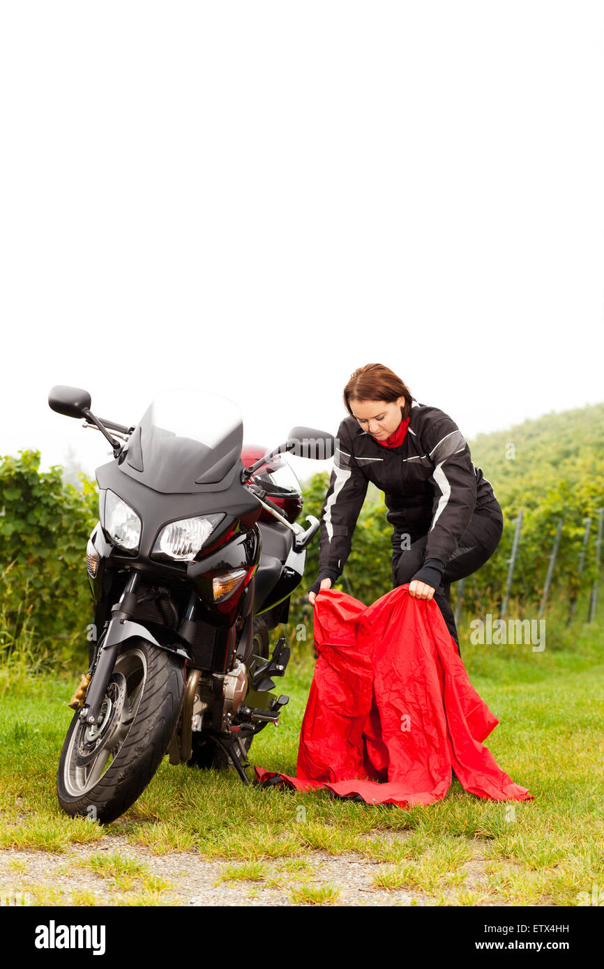 Motorcycle rider puts on rain protection Stock Photo Alamy