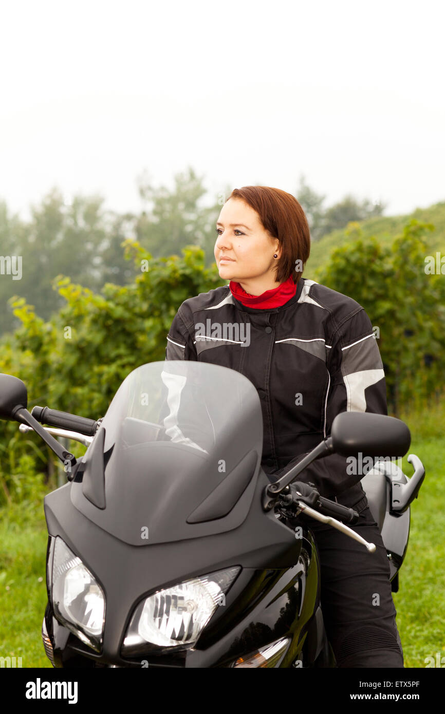 Motorcyclist sitting with view into the distance on a motorcycle Stock Photo