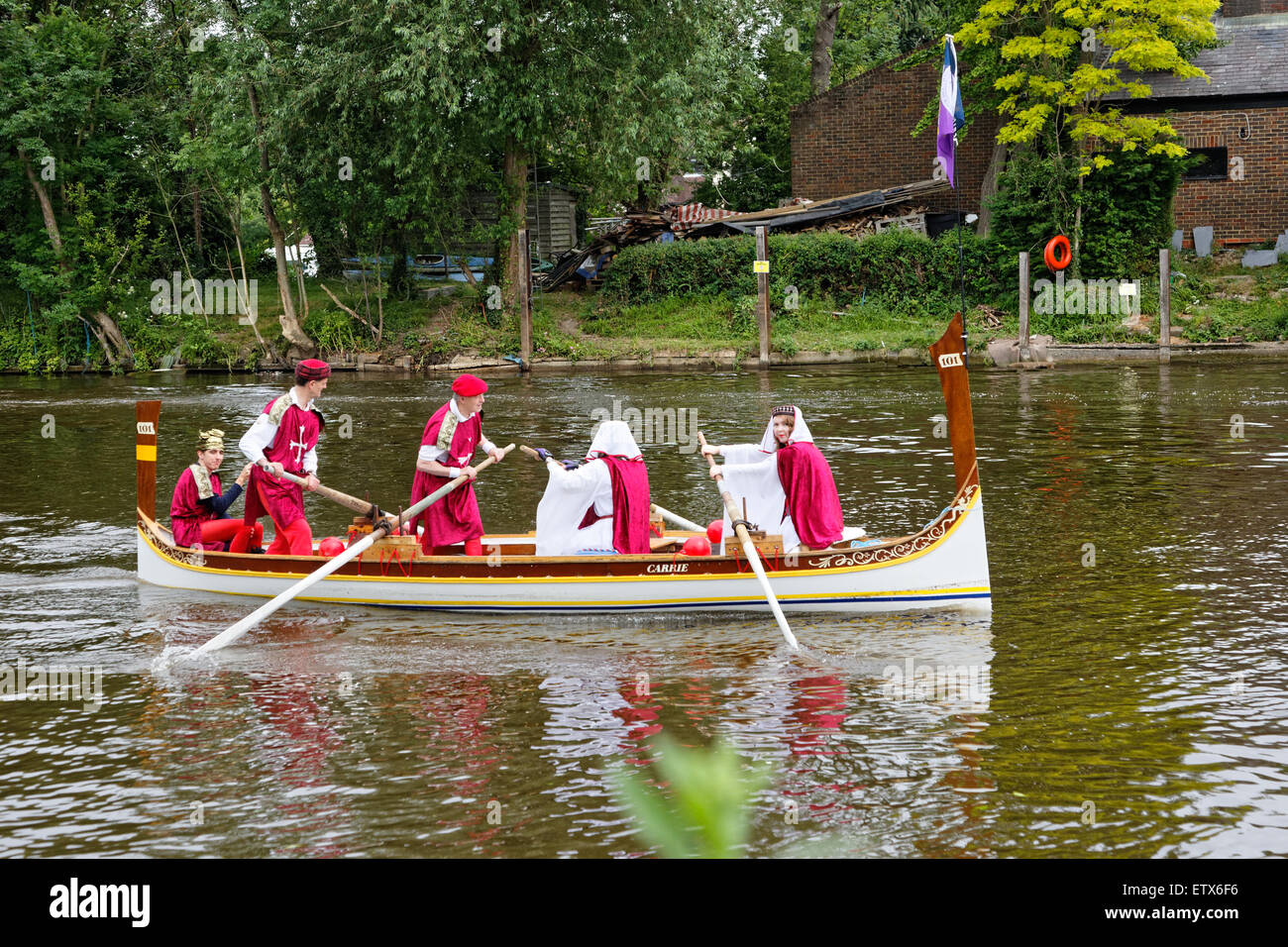 Carrie with rowers in 'medieval' costume runs to join a flotilla of boats in the river procession to Runnymede. Stock Photo