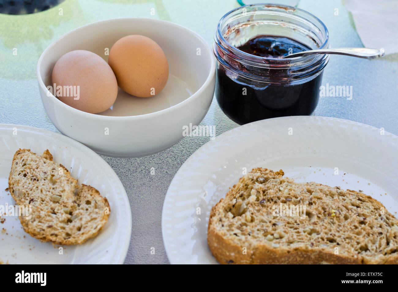 Simple breakfast of boiled eggs, slice of multigrain toast, and homemade jam. Stock Photo