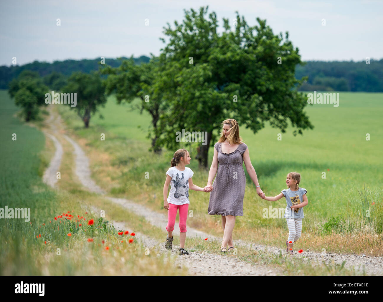 A mother and her two daughters take a walk along a field road during summery 30 degrees Celsius near Prötzel (Brandenburg), Germany, 06 June 2015. Photo: Patrick Pleul/lbn Stock Photo
