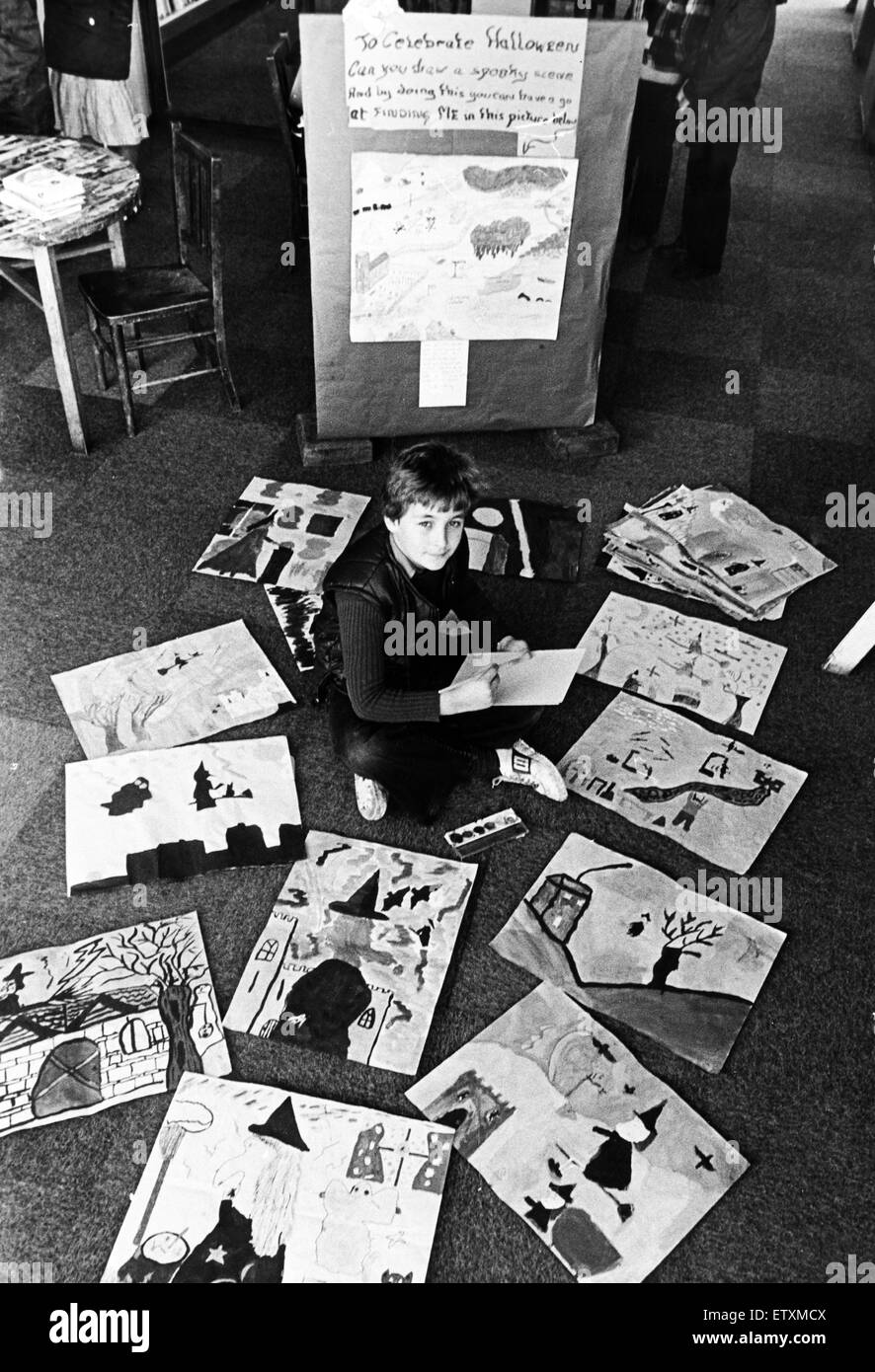 A young boy sitting on the floor among paintings and drawings which have been made by children for Halloween. 29th October 1980. Stock Photo