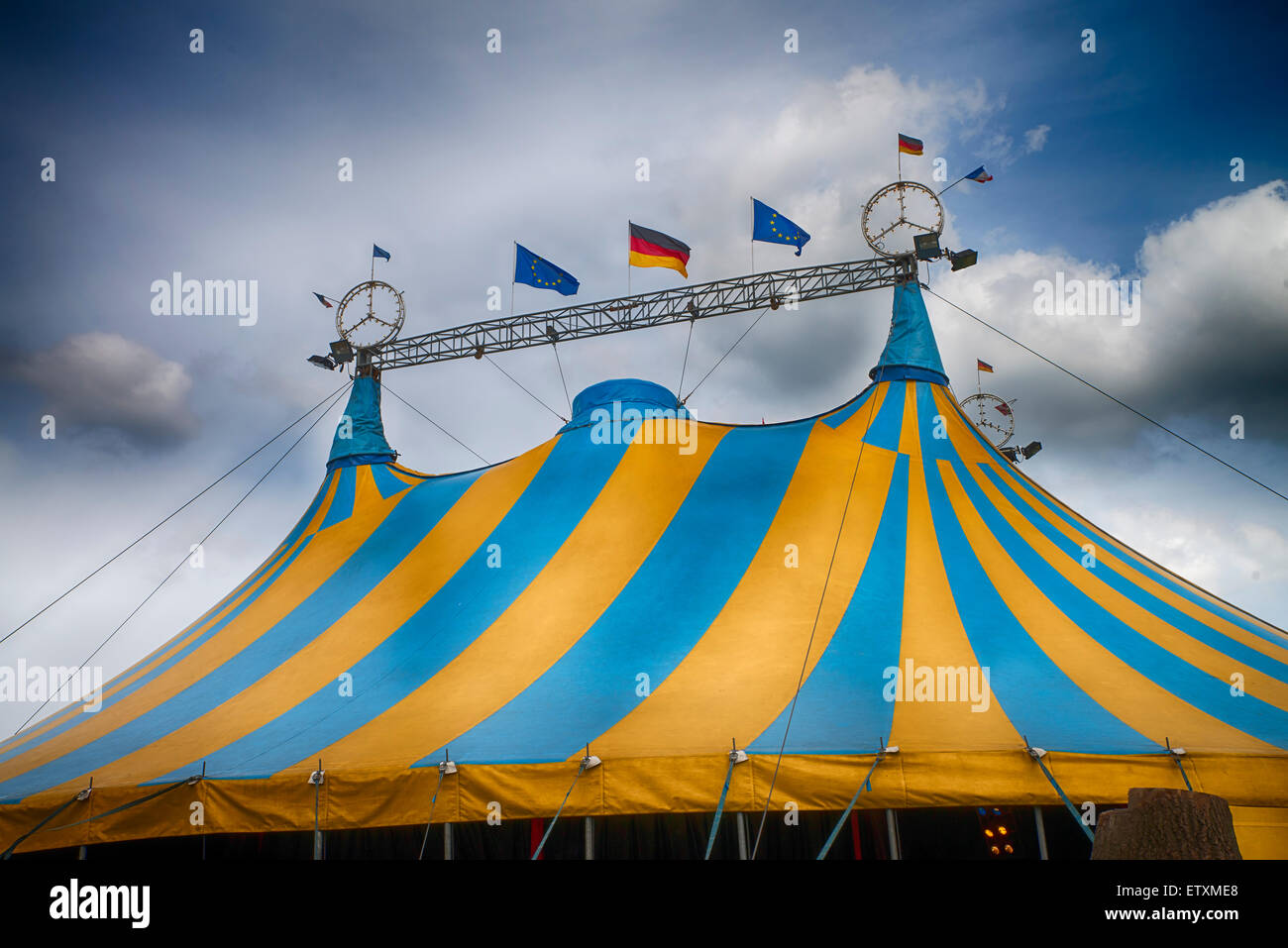 blue and yellow striped circus tent under a blue sky Stock Photo