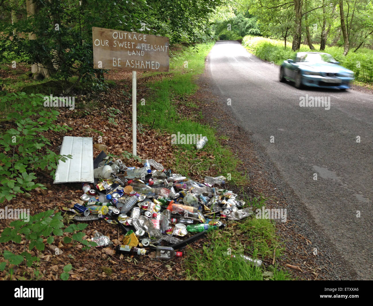 Cannock Chase, Staffordshire, UK. 15th June, 2015. In the countryside around Upper Longdon, Cannock Chase, 'area of outstanding natural beauty' a litter vigilante creates a roadside protest against littering. The mystery person or persons collect rubbish and present it next to a sign reading 'Outrage. Our sweet and pleasant land. Be ashamed.' The rubbish contains mainly alcohol drinks cans and bottles. Credit:  Richard Grange/Alamy Live News Stock Photo