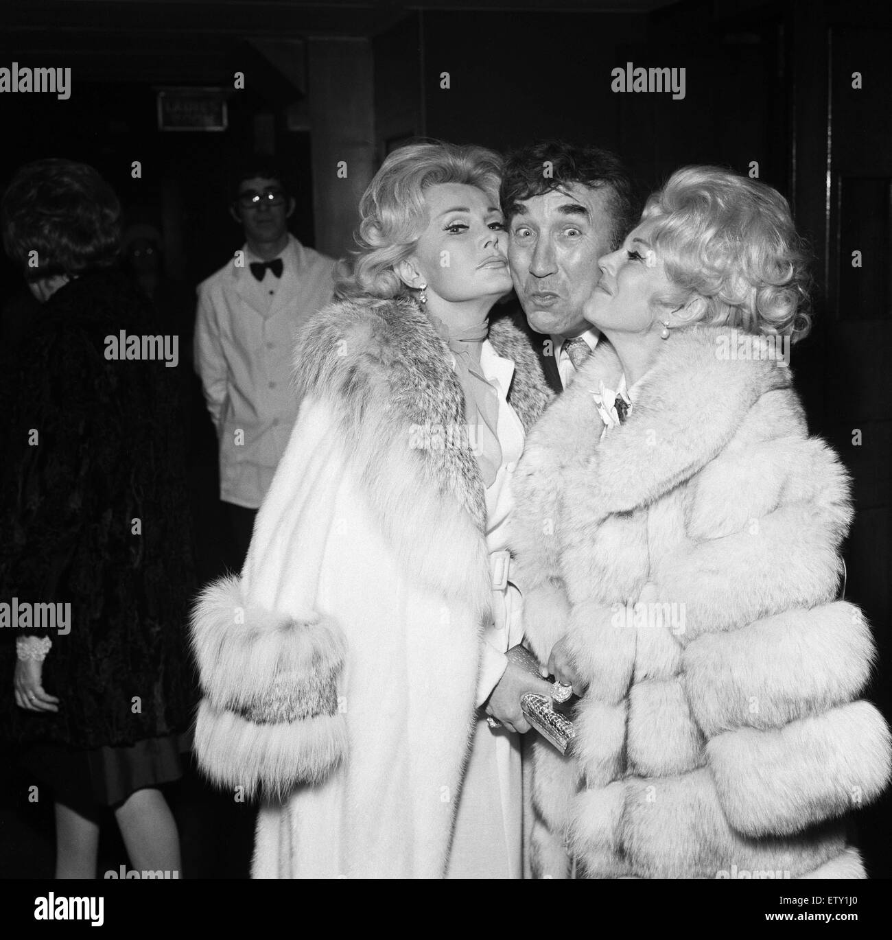 Frankie Howerd, took the two Gabor sisters Eva and Zsa Zsa, out for a different evening's entertainment watching greyhound racing at White City. The trio arrive at the top floor restaurant.  25th March 1972. Stock Photo