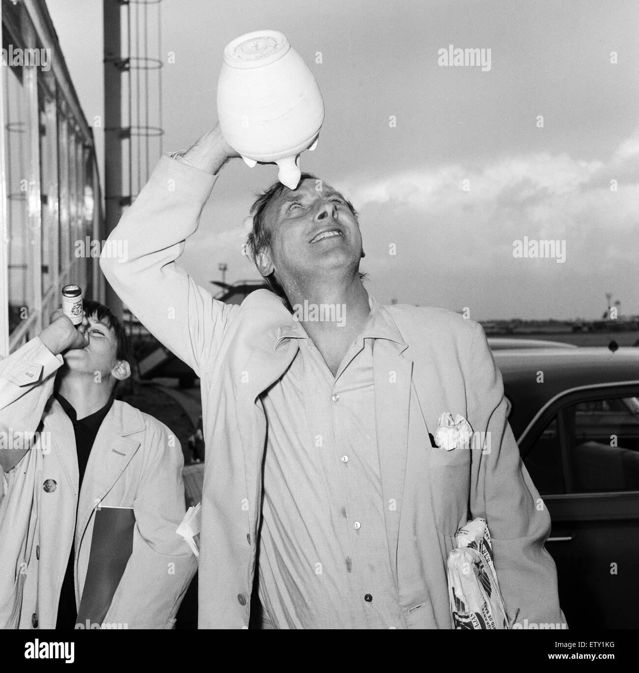Spike Milligan and family back from a three week holiday in Marbella, pictured at London Airport. Spike with a water bottle which he brought back from Spain, and his son Sean (10). 6th September 1965 Stock Photo