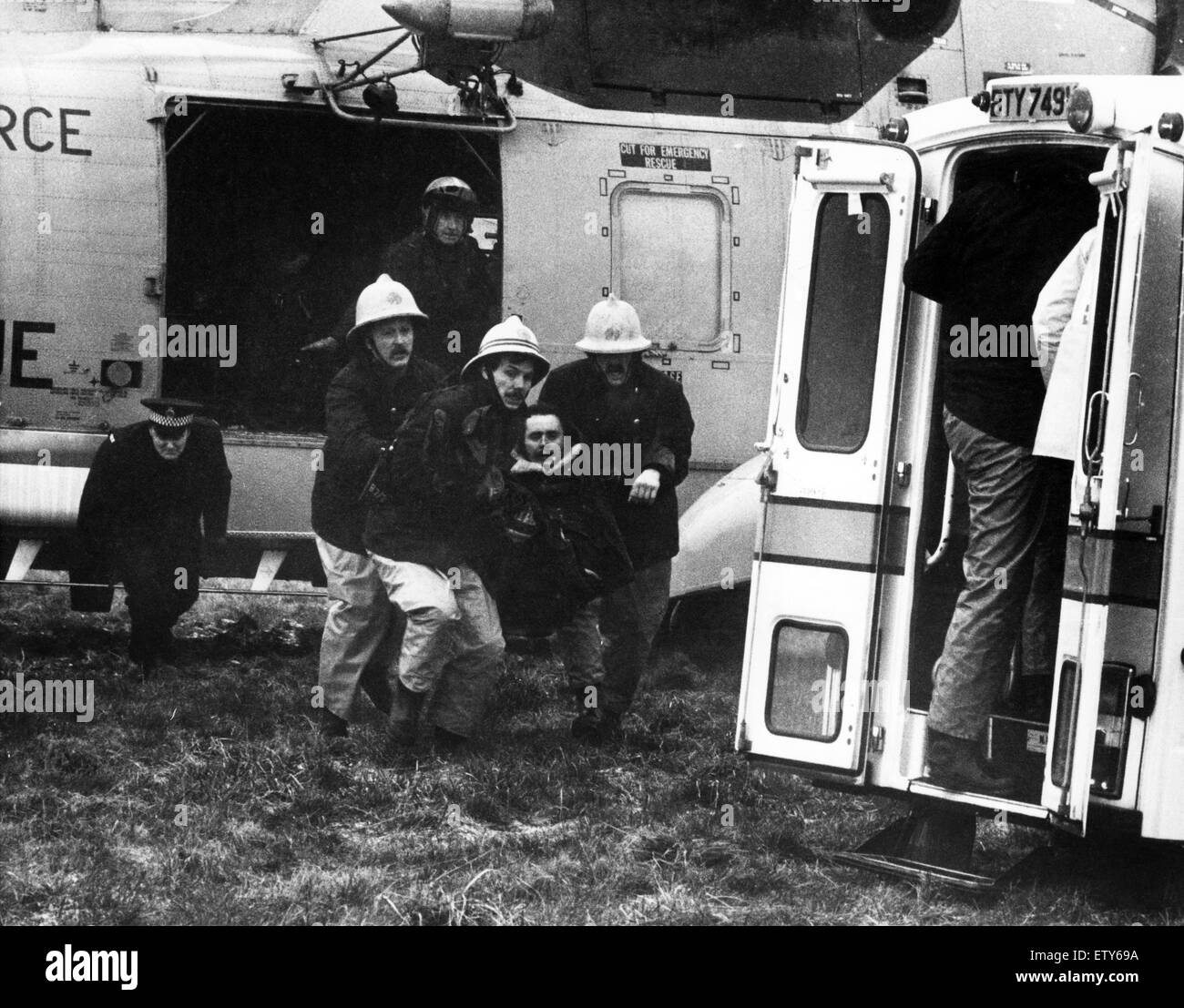 Sea rescue off Cullercoats Harbour in winds of up to Force 7. The double rescue of a fishing boat and then the inshore rescue boat. Firemen carry one of the injured men from the Sea King Helicopter. 22nd February 1981. Stock Photo