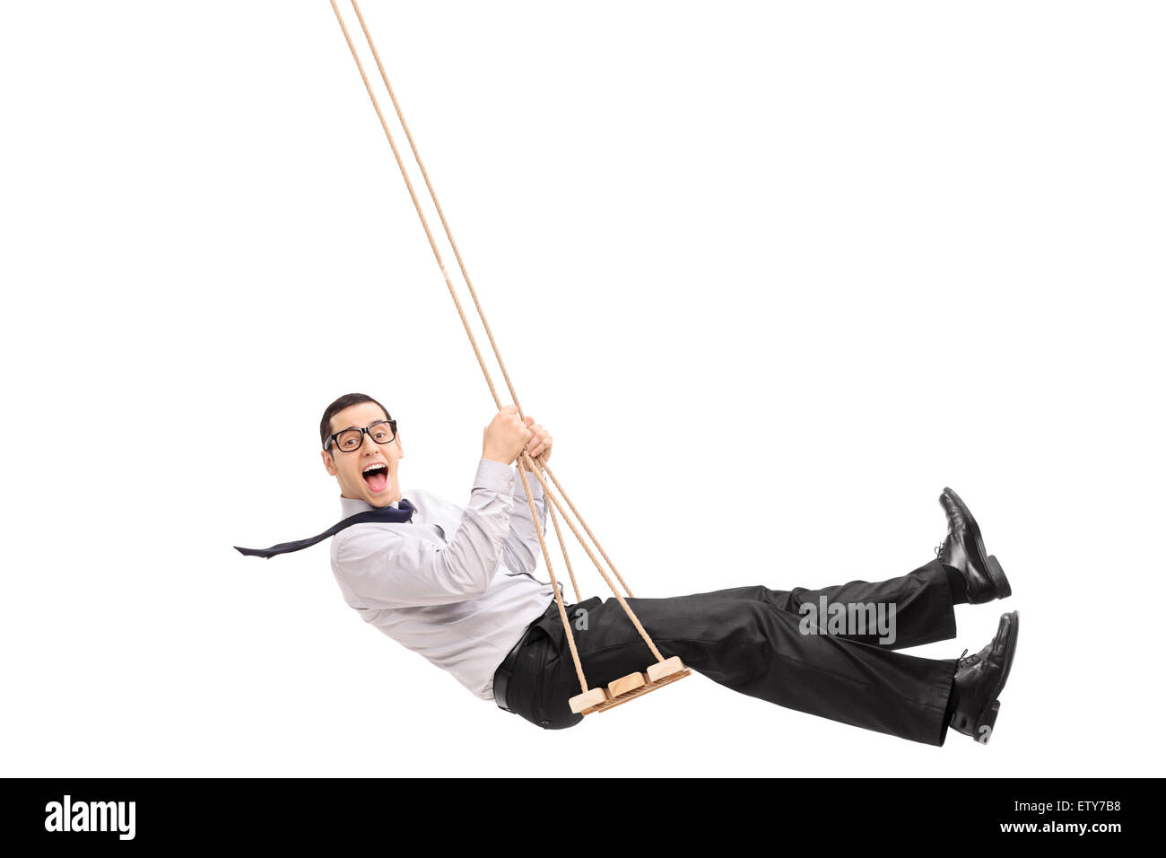 Delighted young man swinging on a swing and looking at the camera isolated on white background Stock Photo