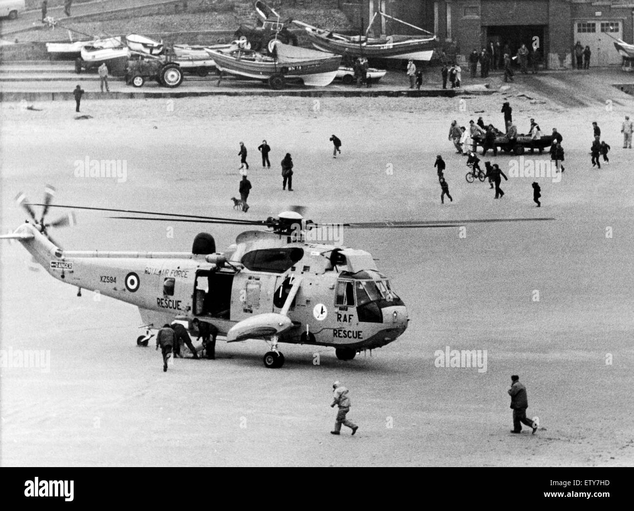 Sea rescue off Cullercoats Harbour in winds of up to Force 7. The double rescue of a fishing boat and then the inshore rescue boat. The Sea King rescue helicopter lands a man on the beach after he was plucked out of the sea. In the background the inshore Stock Photo