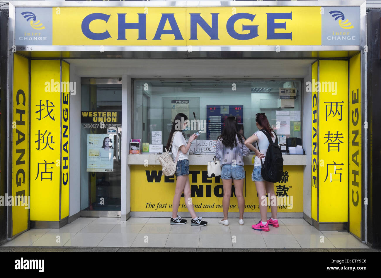 Three young female mainland Chinese tourists at currency exchange shop in Hong Kong Stock Photo