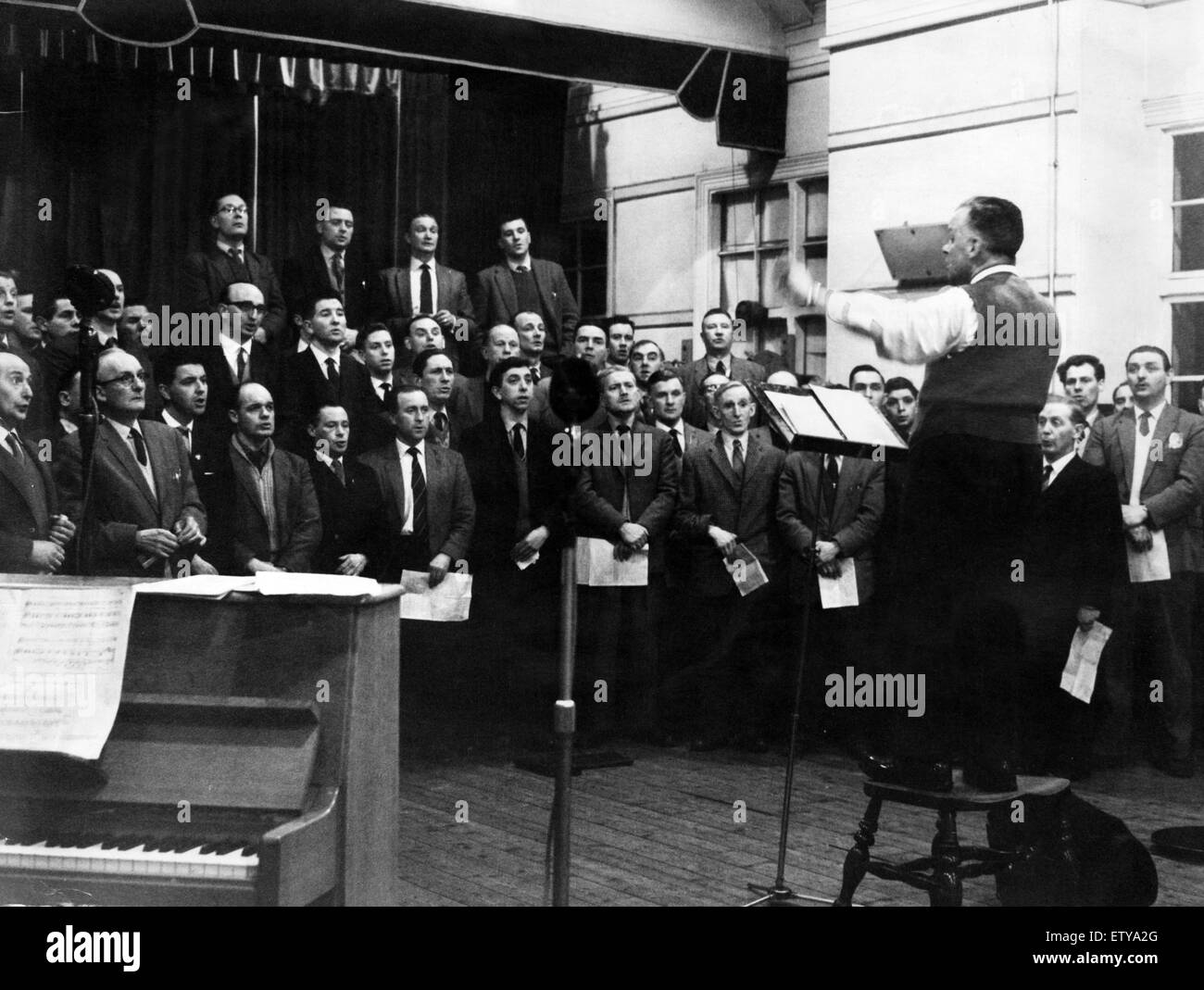 Male Choir 1963. With the natural discipline of well groomed singers members of the Treorchy Male Voice Choir have eyes for nothing else except their conductor Mr John Haydn Davies, during a recording for the BBC Altogether radio series, which will be the Stock Photo