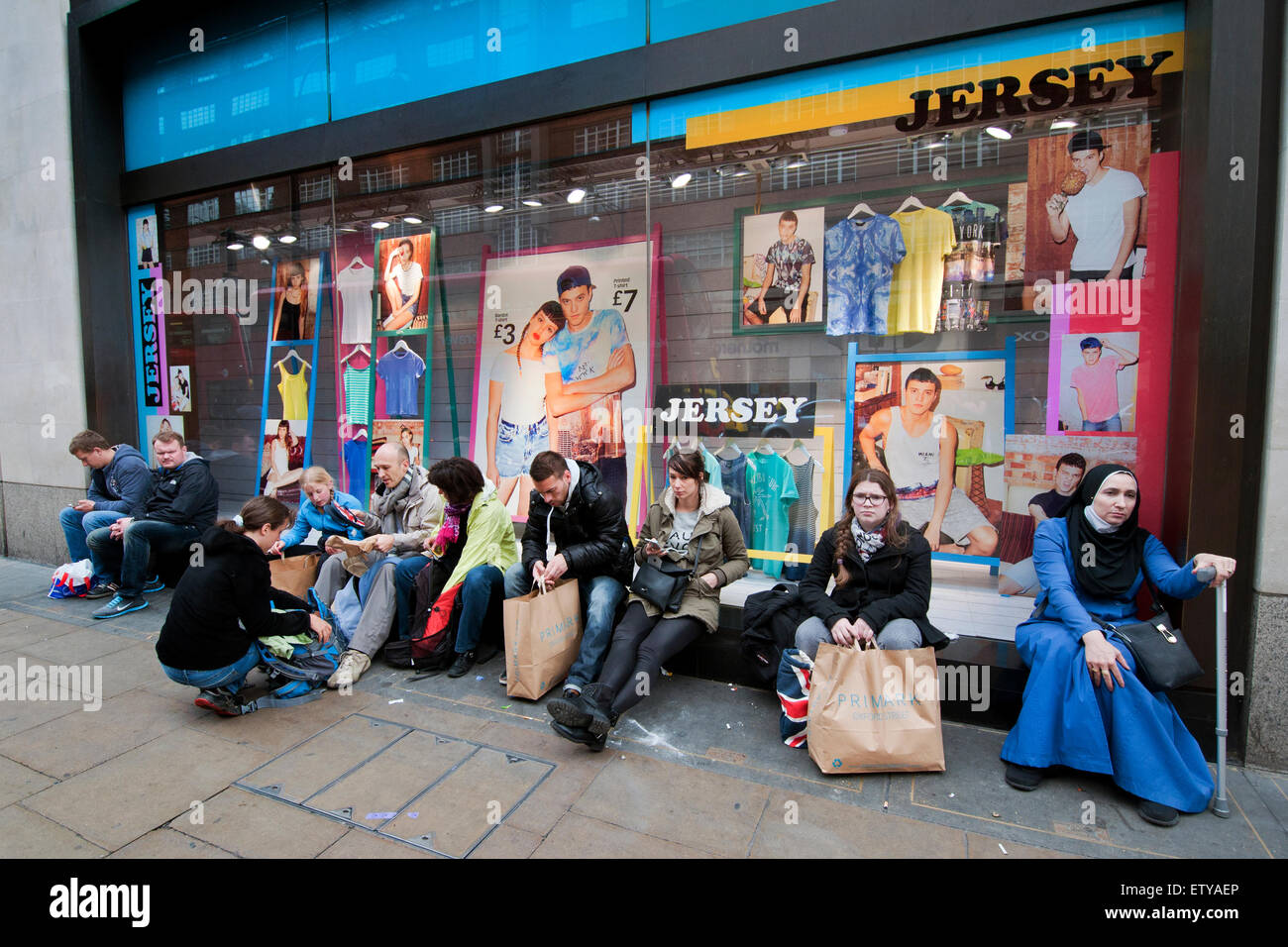 Shoppers sitting outside Primark in Oxford Street tired from bargain ...
