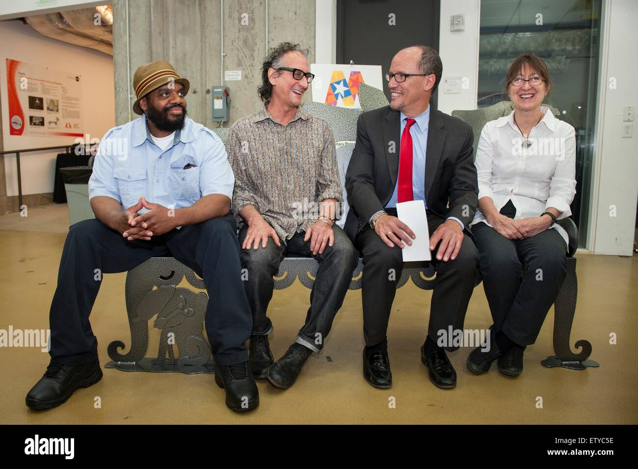 U.S. Secretary of Labor Thomas Perez talks to artist James Simon (center left), welder Ramone Patterson (left) and project manager Karen Antonelli (right) as they sit on a bench the three made at the Center for Robotics' Planetary Robotics High Bay at Carnegie Mellon University May 29, 2015 in Pittsburgh, Pennsylvania. Stock Photo