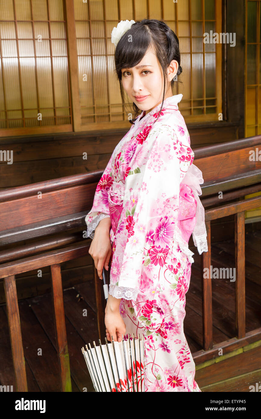 Asian woman wearing a kimono in front of Japanese house holding ...