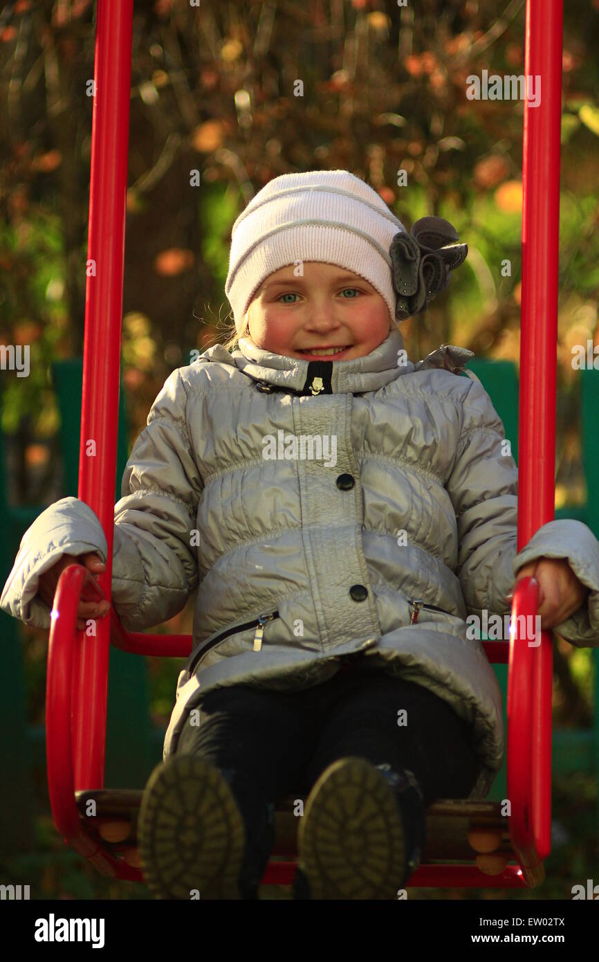 little and very glad girl plays on the swing Stock Photo