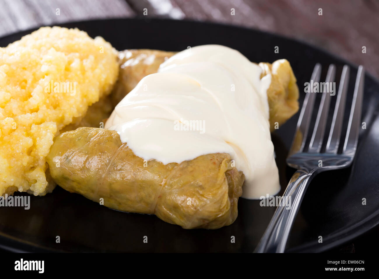 Cabbage rolls filled with minced meat and rice on plate with polenta, over wooden table Stock Photo