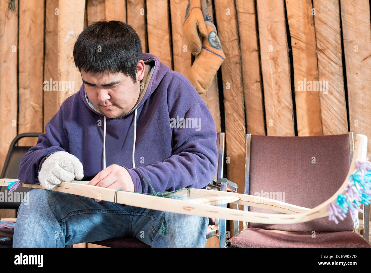Young indigenous man making a traditional snowshoe , Northern Quebec