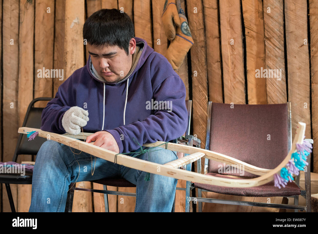 Young indigenous man making traditional snowshoes , Northern Quebec, Canada Stock Photo