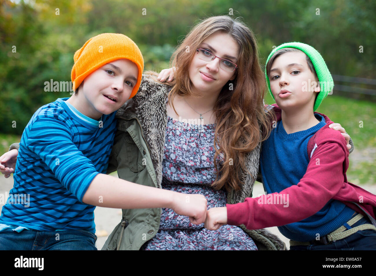 two boys and a teenage girl sitting on a wall Stock Photo