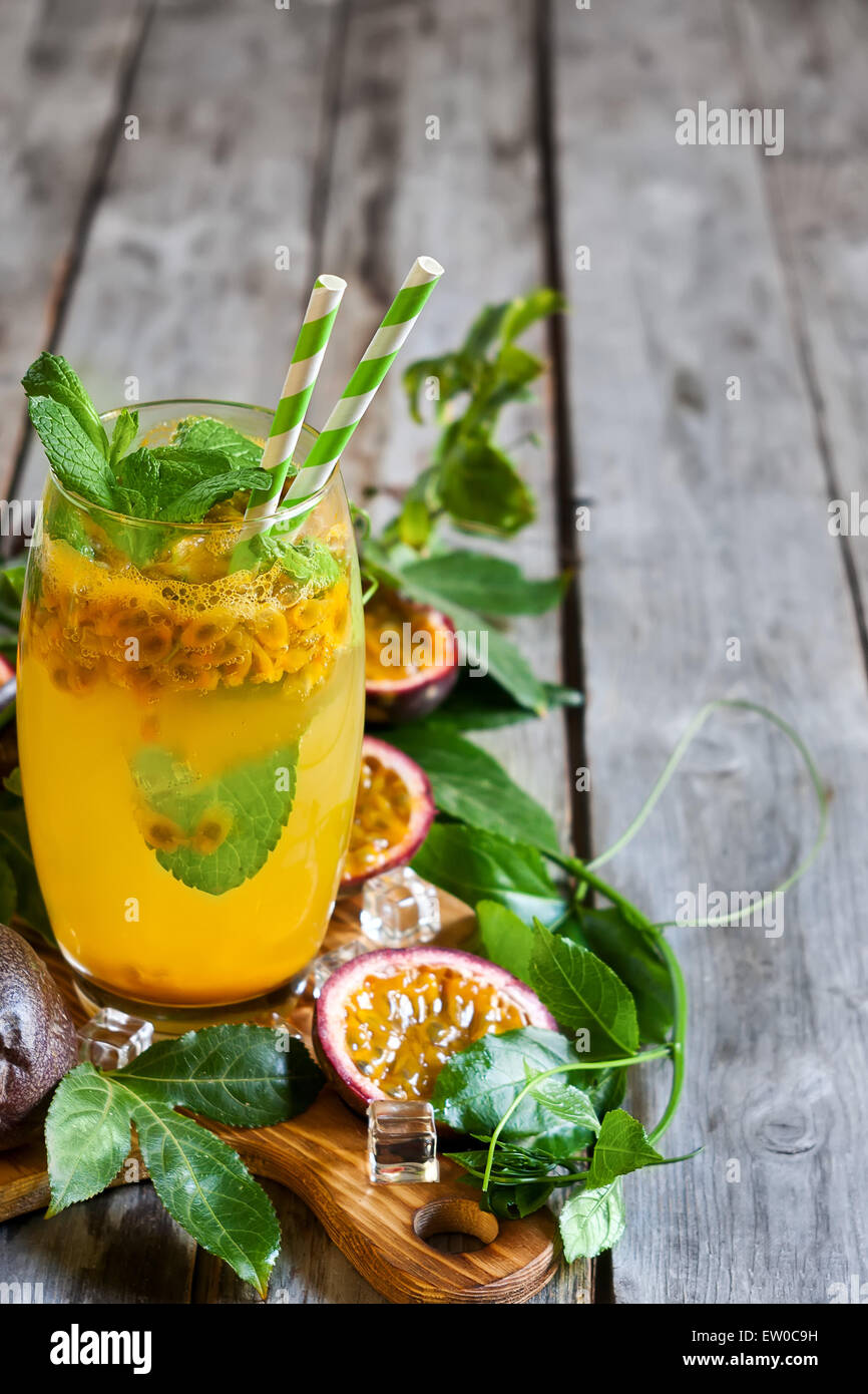 Homemade lemonade with passionfruit, mint leaves and ice cubes on old wooden background. Copy space background. Stock Photo