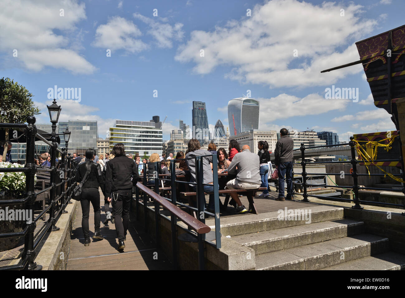 People sitting outside bar with City skyline in background on the banks of the River Thames in Southwark London United Kingdom Stock Photo