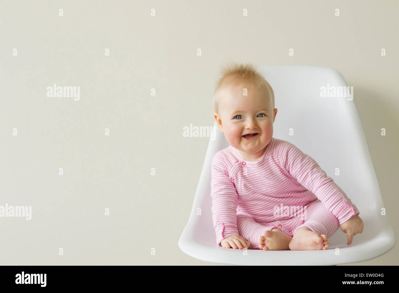 baby girl sitting on white eames chair Stock Photo