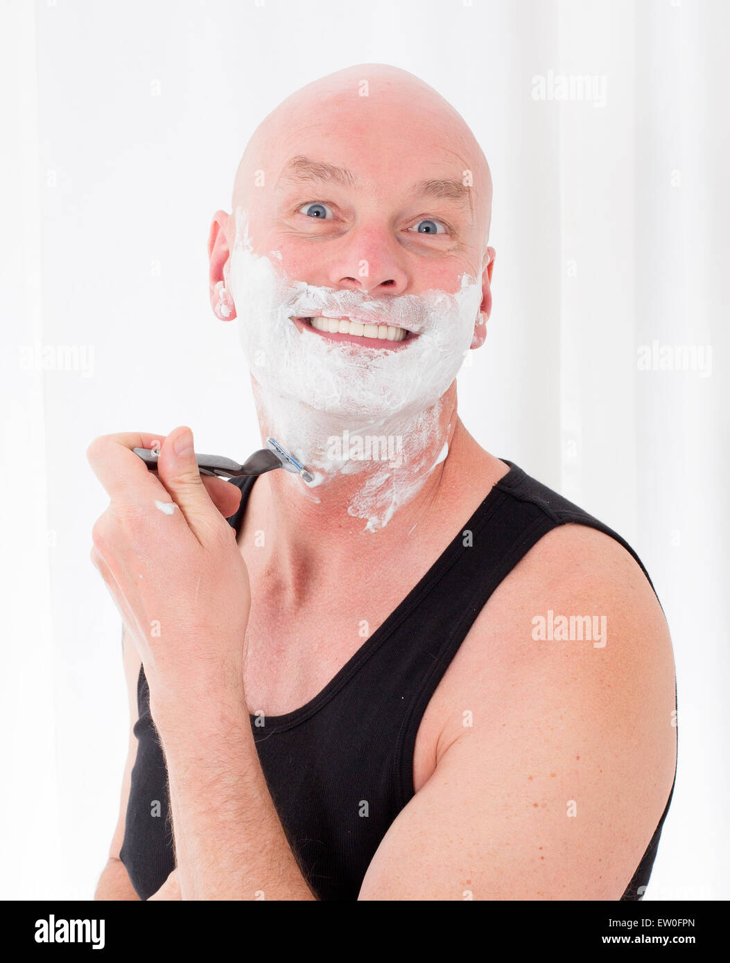 bald-headed man shaving and smiling Stock Photo