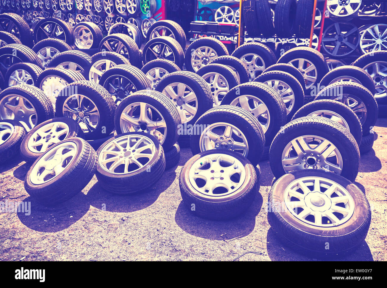 Vintage style picture of car wheels and aluminum rims on the street. Stock Photo