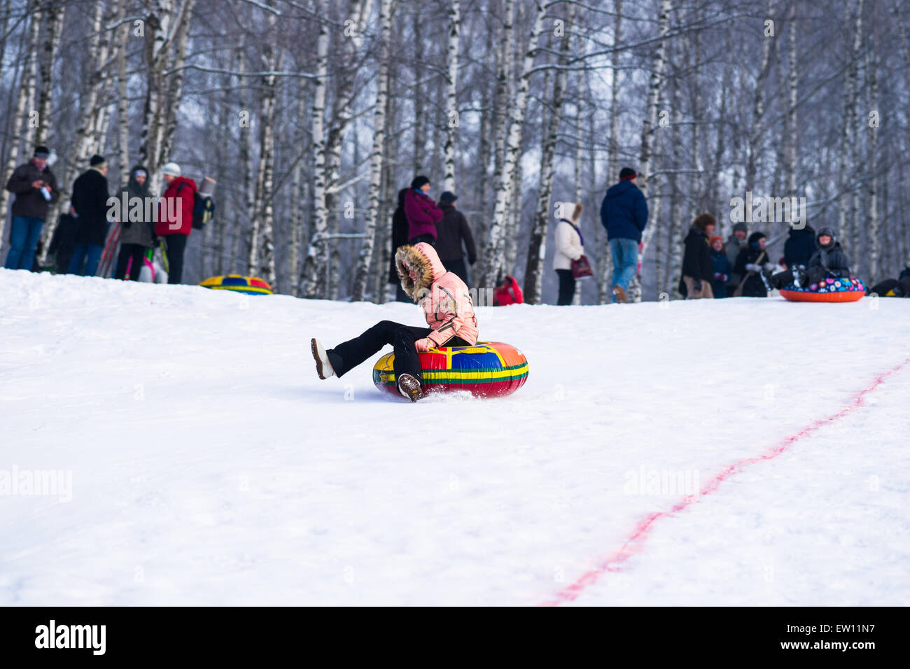 Unidentified, unrecognizable woman slides down the hill using a tubing on a sunny and frosty
