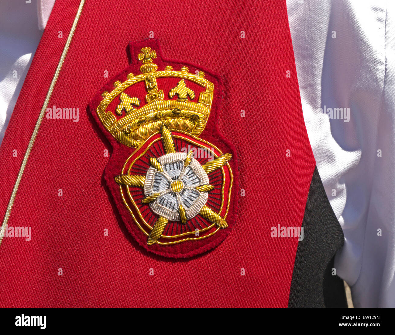 Tudor Crest Hampton Court Palace uniformed tourist information guide crest/emblem on official guide’s red waistcoat close up view texture sunlit Stock Photo