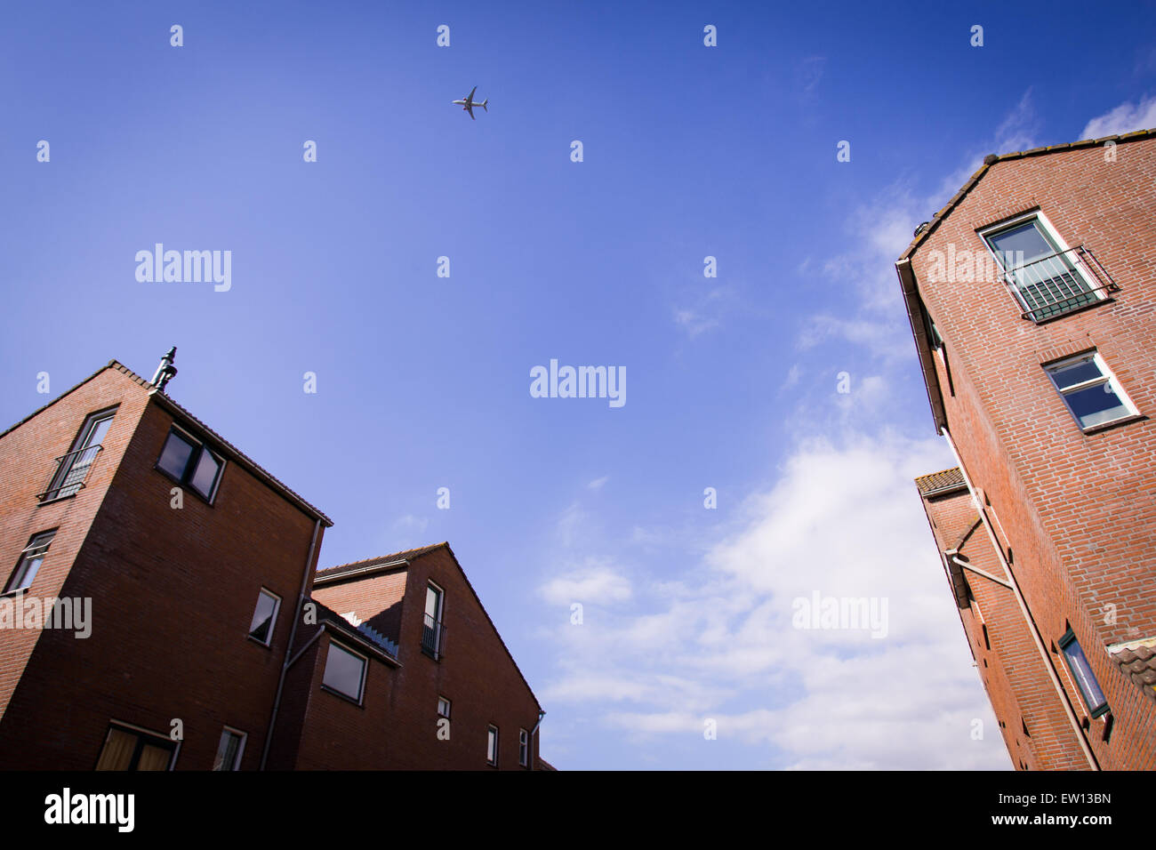 A commercial airplane is seen flying over a Dutch suburb. Stock Photo