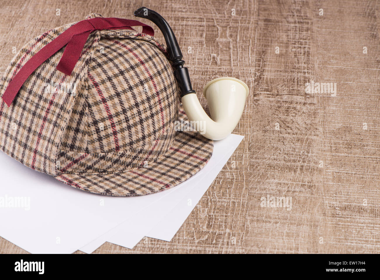 Deerstalker or Sherlock Hat and Tobacco pipe on Old Wooden table. Stock Photo